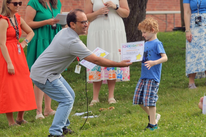 man handing certificate to boy