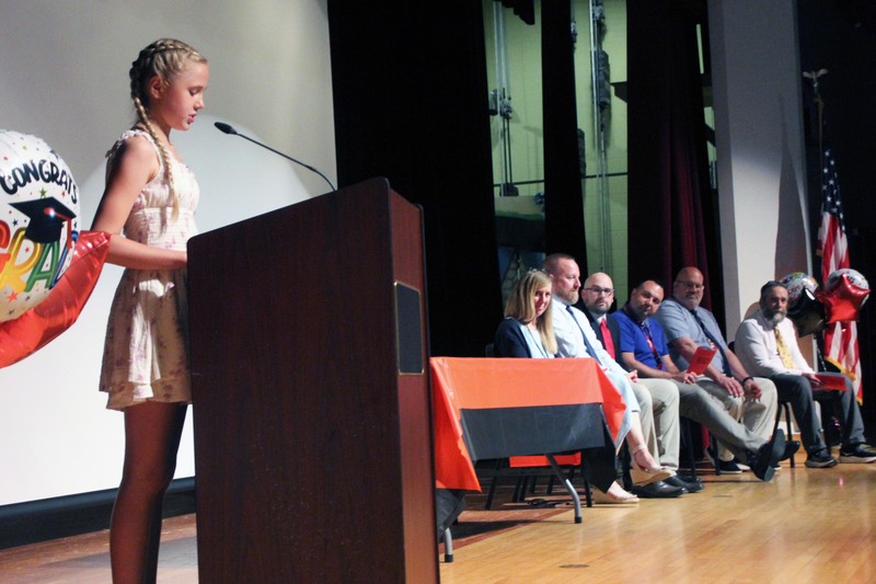 girl reading while school administrators look on